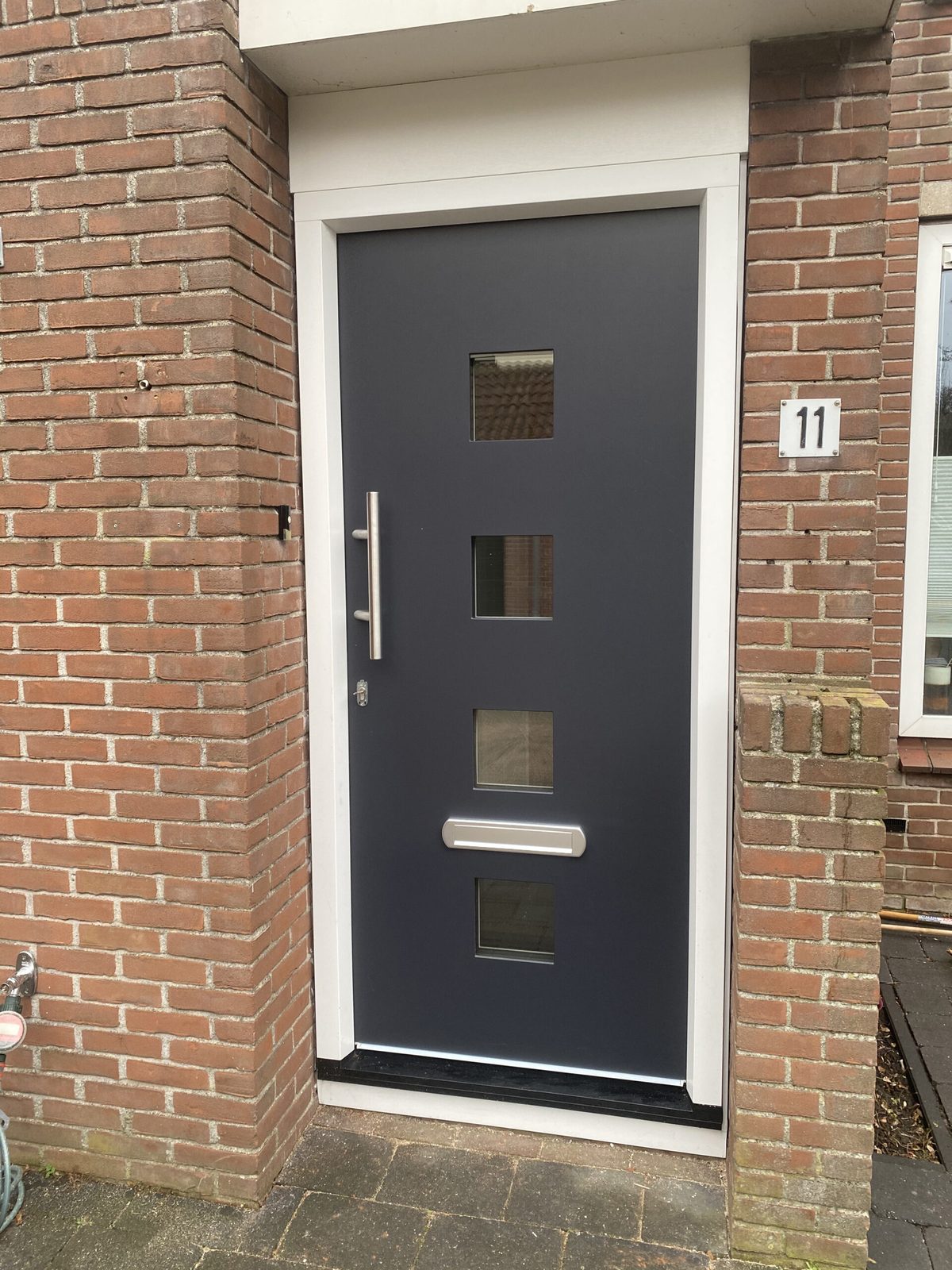 Antraciete voordeur met vier glasvlakken en een rvs greep