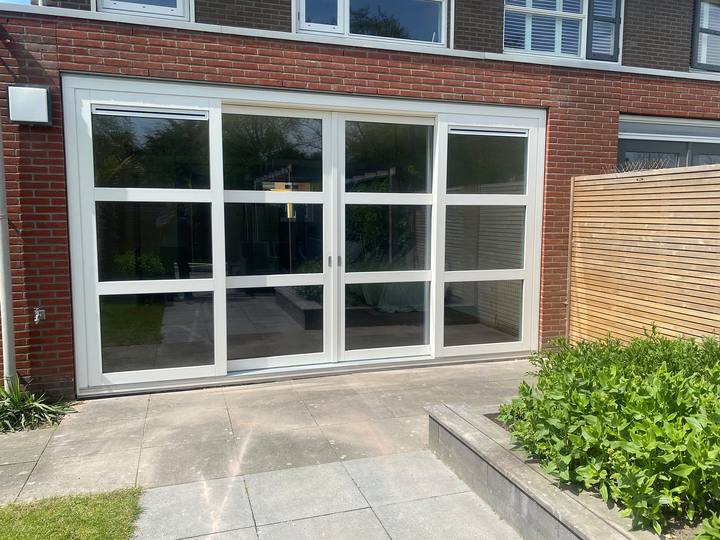 Grote witte pui met openslaande deuren en roedeverdeling