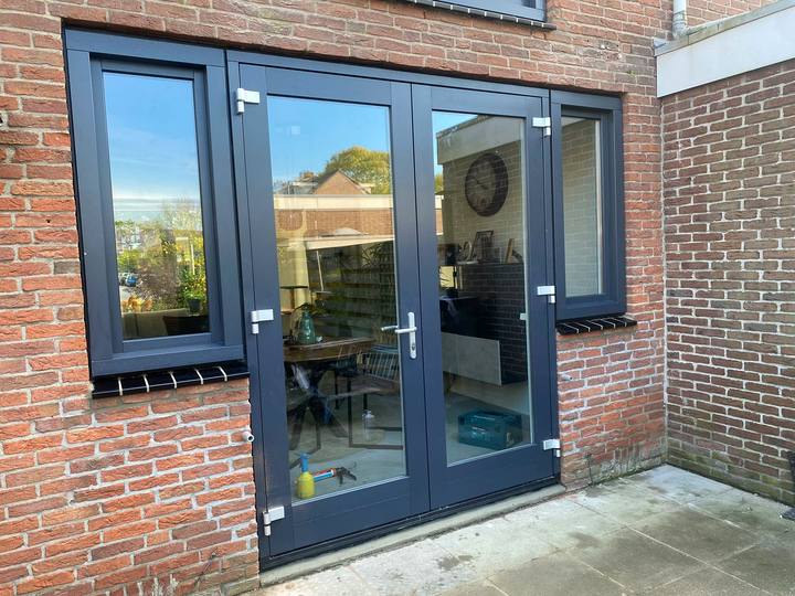 Antraciete openslaande tuindeuren met zijramen in een bakstenen achtergevel