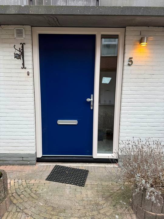 Diepblauwe voordeur met zijlicht in een witte gevel
