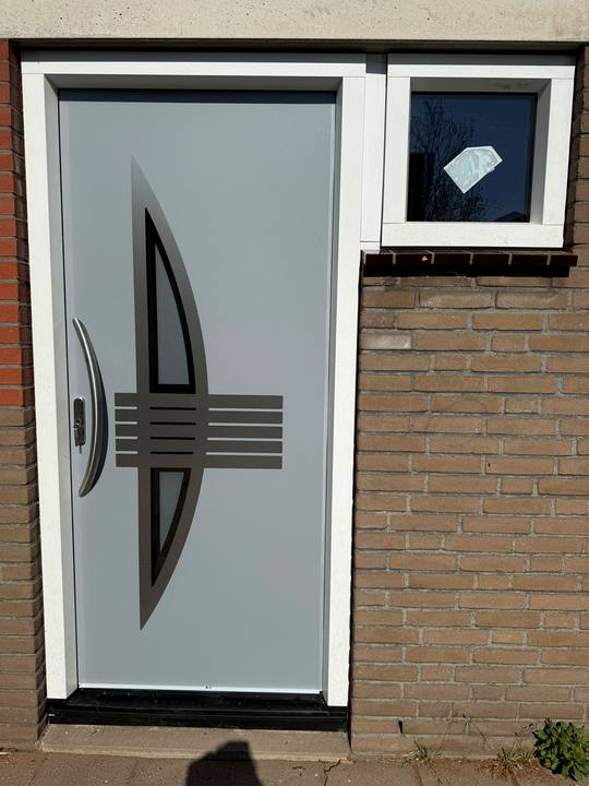 Lichtgrijze voordeur met een gebogen glasdesign en rvs strepen