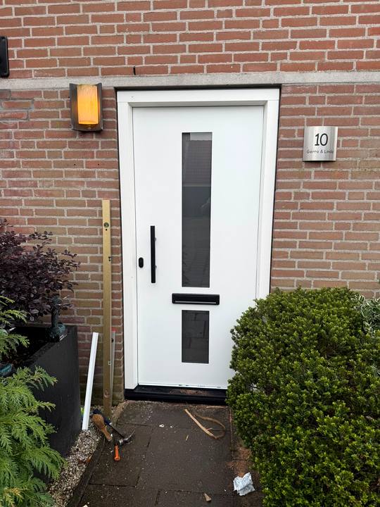 Witte voordeur met smalle glasstroken en zwart beslag