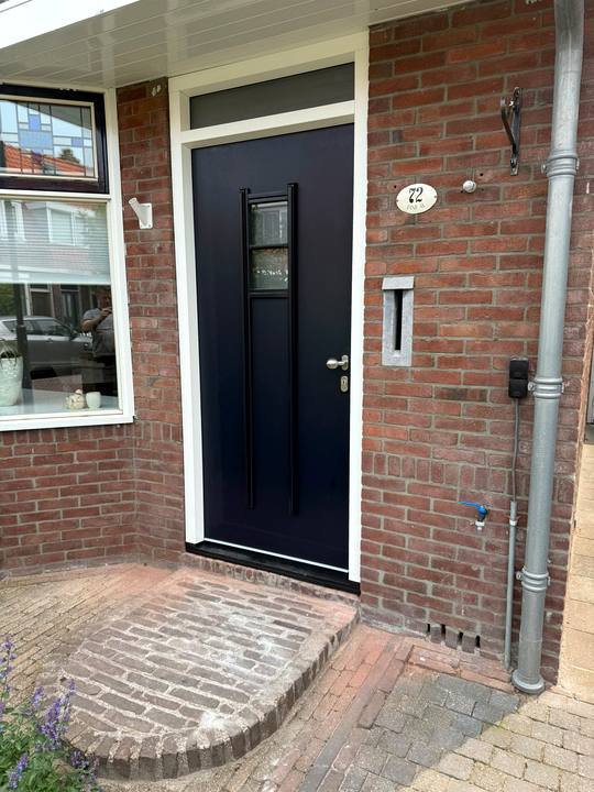 Zwarte voordeur met smalle glasstrook en bovenlicht