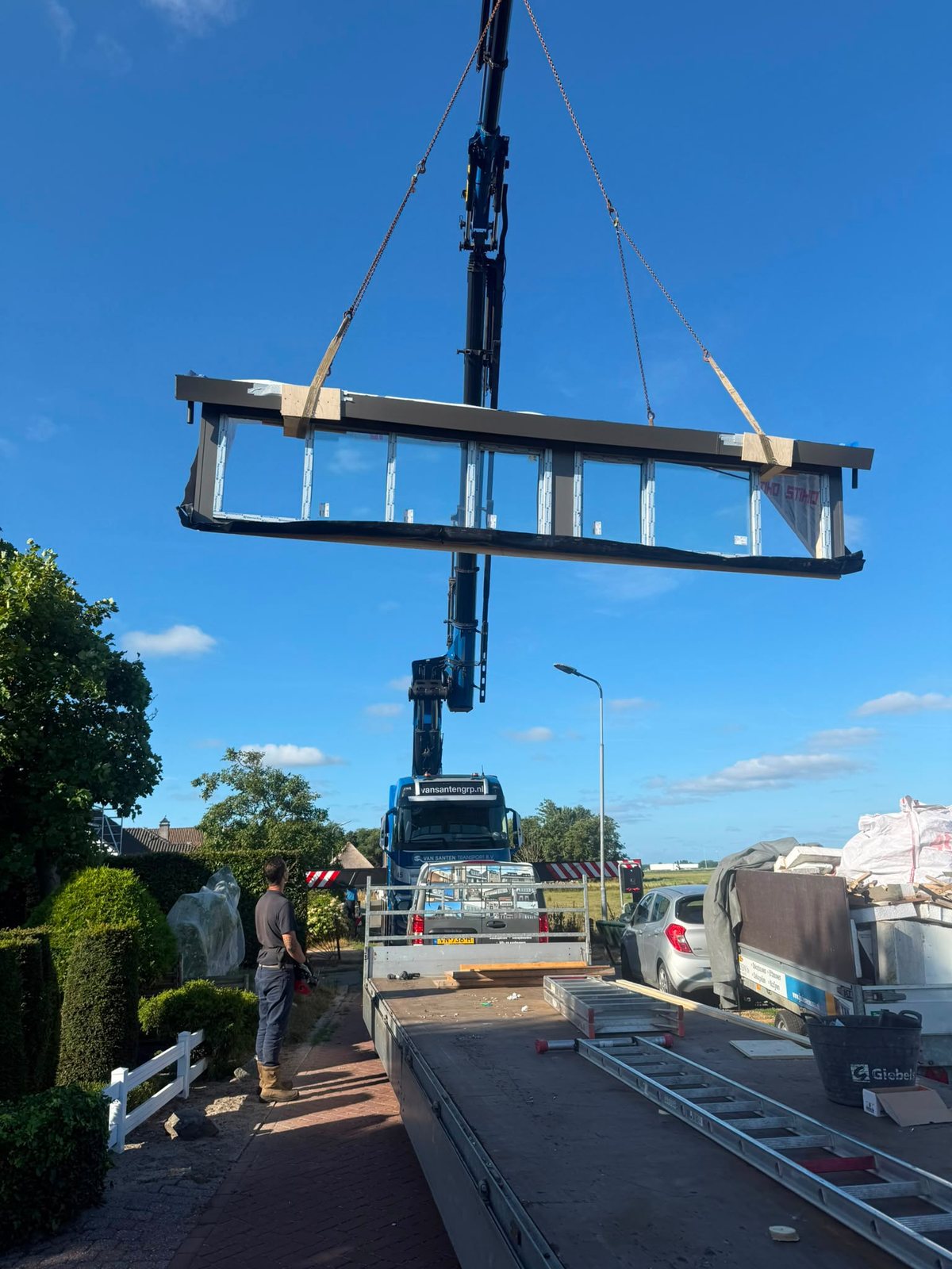 Dakkapel hangt aan de kraan en wordt boven de woning naar het dak getild