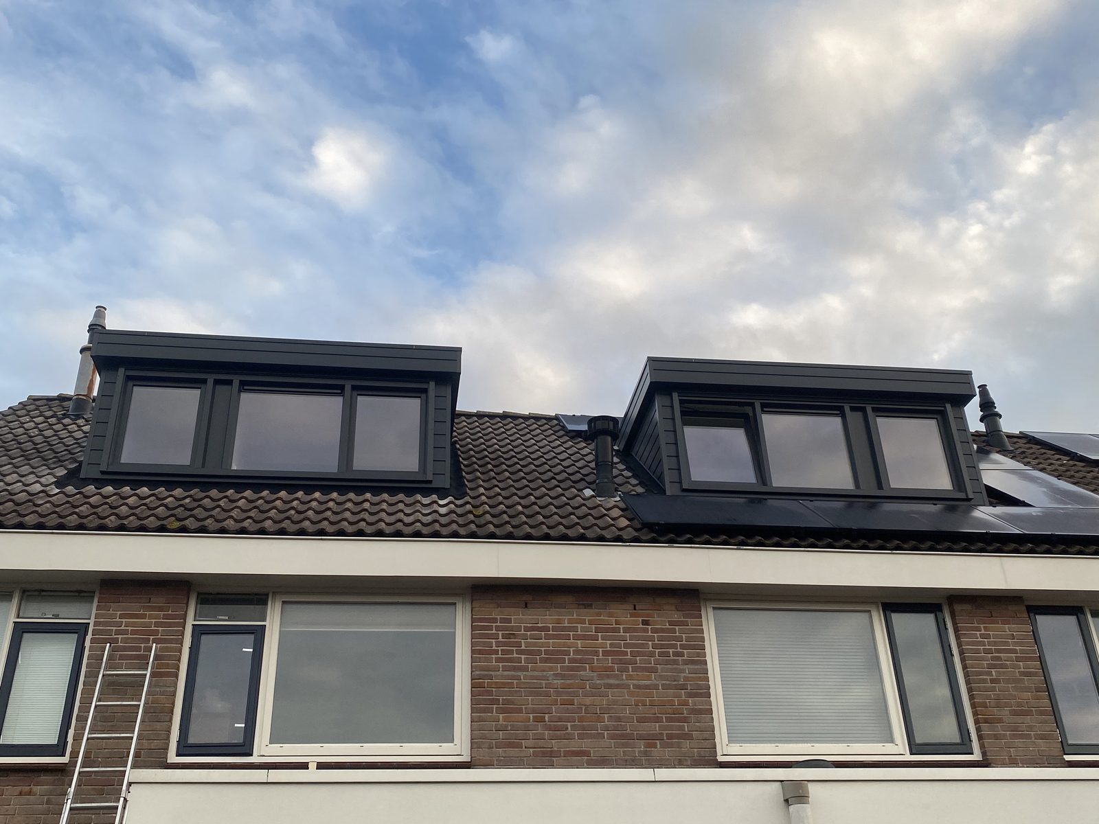 Twee antraciete dakkapellen naast elkaar op hetzelfde dakvlak