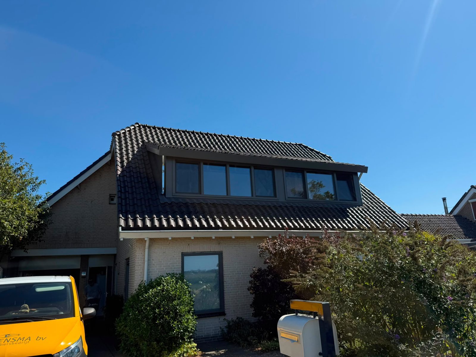 Brede antracietkleurige dakkapel op het voordakvlak van een woning