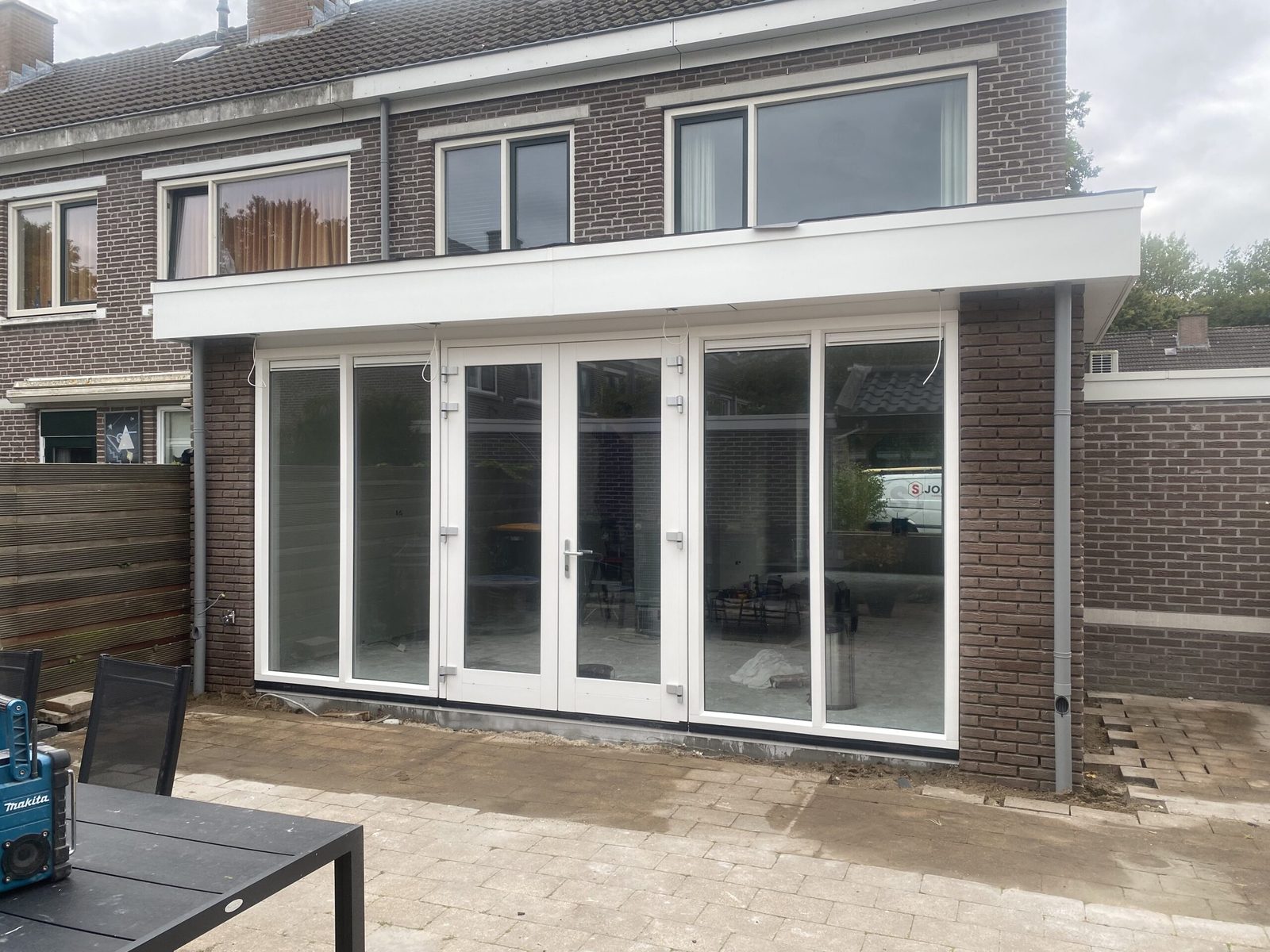 Uitbouw aan de achtergevel met witte openslaande deuren naar de tuin