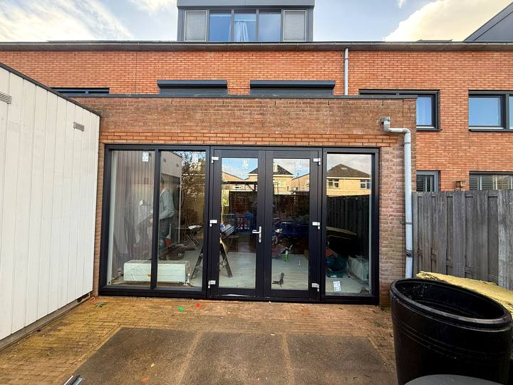 Aanbouw met een brede glazen pui en openslaande deuren naar de tuin