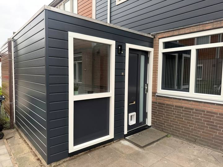 Kleine aanbouw met antraciete gevelbekleding en witte kozijnen