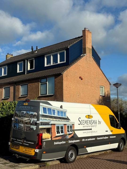 Opgeleverde dakopbouw met blauwe gevelbekleding, met de bus van Siemensma voor de woning